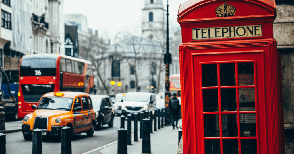 Busy street in England right next to a red telephone booth